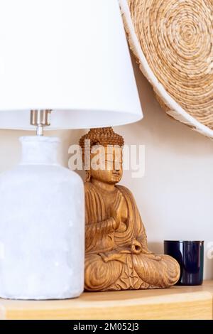 Éléments intérieurs décoratifs de style ethnique avec lampe de table blanche, statue de Bouddha en bois et jardinière murale en osier (photo verticale) Banque D'Images