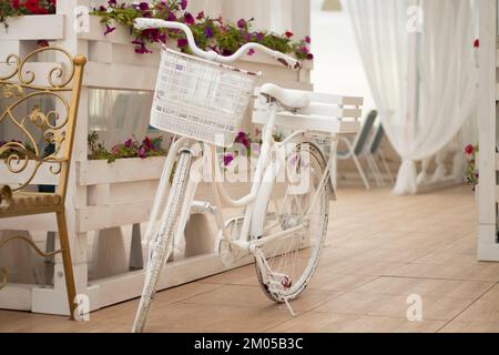 un vélo blanc avec une boîte à fleurs se trouve près d'un café Banque D'Images