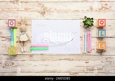 Page de coloriage, stylos-feutres et jouets sur fond de bois Banque D'Images