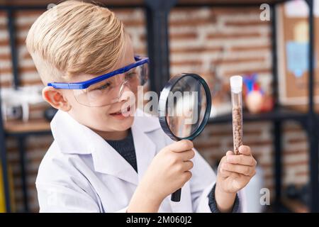 Adorable enfant étudiant regardant un tube à essai avec une loupe en classe Banque D'Images