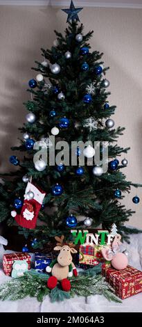 Noël, nouvel an intérieur avec fond de mur en brique rouge, sapin décoré avec guirlandes et balles, tiroir foncé et figurine cerf Banque D'Images