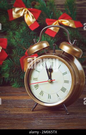 Horloge du nouvel an et branche de sapin de Noël décorée d'arcs rouges. Filtré dans un style rétro Banque D'Images