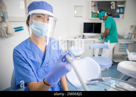 Une femme dentiste de la clinique tient la perceuse pendant que sa collègue se tient derrière Banque D'Images