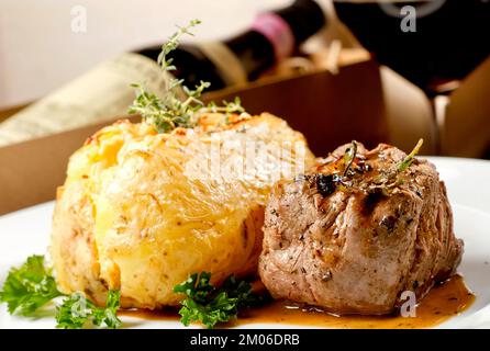 Filet de bœuf mignon avec sauce et pomme de terre farcie servi sur une assiette accompagnée d'un verre de vin rouge et d'une bouteille. Restaurant de qualité supérieure cuisine gastronomique Banque D'Images