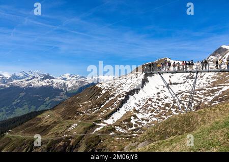 Montagnes dans les Alpes suisses avec des personnes debout sur la plate-forme de la première falaise de Grindelwald en attendant leur photo à prendre. Banque D'Images
