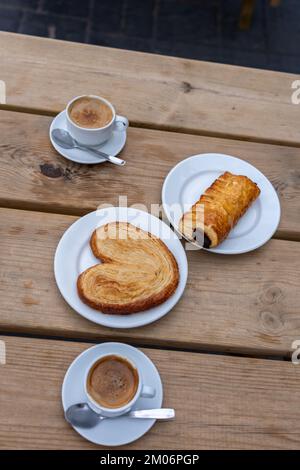 Vue de dessus de deux tasses à café avec 2 produits de boulangerie sur une table en bois Banque D'Images