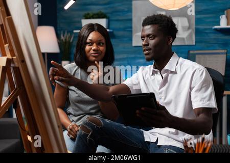 Esquisse professionnelle enseignante enseignant enseignant enseignant d'enseignement des techniques d'arts à l'artiste masculin. Professeur de dessin personnel corrigeant des œuvres d'art d'un étudiant afro-américain dans un atelier d'arts plastiques. Banque D'Images