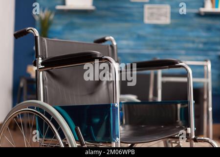 Fauteuil roulant placé pour une personne handicapée dans une chambre vide de la maison de soins infirmiers. Espace lumineux avec marcheur de soutien et assistance dans le centre de vie assisté aux personnes âgées, réhabilitation de santé. Banque D'Images