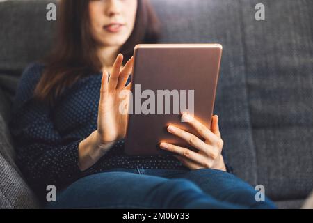 Femme méconnue se relaxant sur le canapé tout en faisant des achats en ligne sur la tablette numérique Banque D'Images