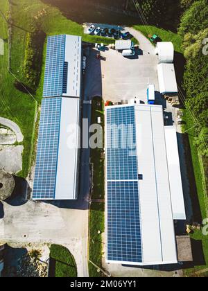 Photo verticale haut vers le bas vue aérienne panneaux solaires sur le toit de deux entrepôts dans la campagne Banque D'Images