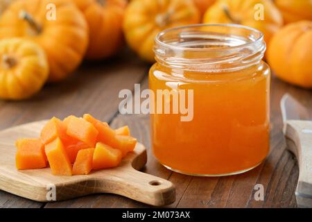 Pot de confiture de citrouille saine. Pâte de citrouille hachée sur une planche à découper. Citrouilles en arrière-plan. Banque D'Images