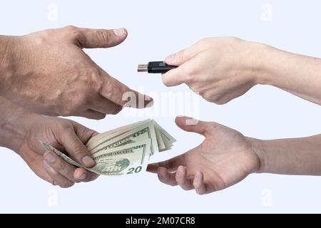 Échangez un dispositif de stockage contre de l'argent entre deux personnes, où seules leurs mains et leurs avant-bras sont visibles sur un fond blanc. Banque D'Images