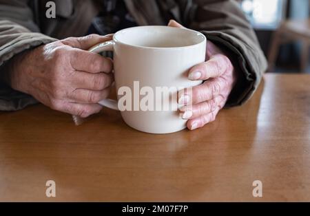 Une vieille femme tient une tasse de café chaud dans ses mains. Gros plan sur la main d'une femme âgée tenant une tasse de thé ou de café. CopySpace pour le texte, sélectionnez Banque D'Images