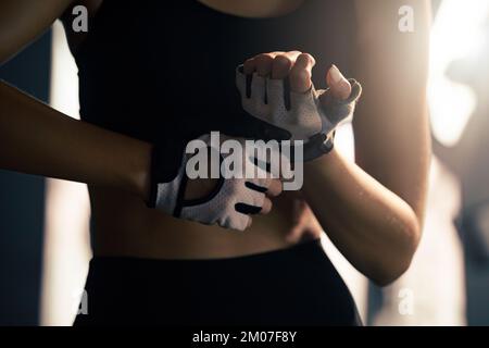 Une femme met des gants de fitness pour faire de l'exercice à la salle de gym. Banque D'Images