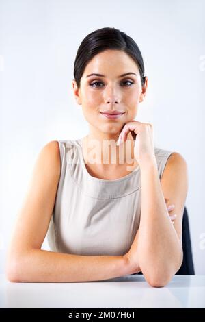 Portrait de la confiance des entreprises. Portrait d'une jeune femme assise sur un fond gris. Banque D'Images