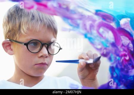 Créativité et talent. Peinture de petit garçon concentrée sur le verre et la création d'œuvres d'art. Banque D'Images