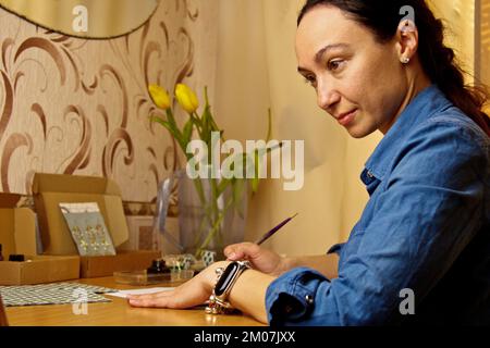 Une fille indienne écrit avec un stylo à encre. papeterie sur un bureau en bois. leçons d'orthographe et exercices de calligraphie. documents administratifs au bureau. l'étudiant écrit un let Banque D'Images