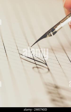 la main féminine écrit avec le stylo inky sur une feuille de papier blanche avec des rayures. papeterie sur le bureau vue rapprochée du dessus. leçons d'orthographe et calligraphie effort Banque D'Images