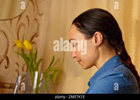 Une fille indienne écrit avec un stylo à encre sur une feuille de papier blanche. papeterie sur un bureau en bois. leçons d'orthographe et exercices de calligraphie. la paperasserie dans l'offic Banque D'Images