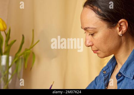 Une fille indienne écrit avec un stylo à encre. papeterie sur un bureau en bois. leçons d'orthographe et exercices de calligraphie. documents administratifs au bureau. l'étudiant écrit un let Banque D'Images