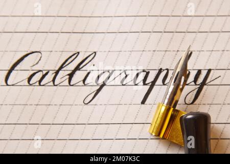 la calligraphie de mot est écrite avec un stylo d'encre sur une feuille de papier blanche avec des bandes dessinées. papeterie vue rapprochée du dessus. leçons d'orthographe et calligraphie e Banque D'Images