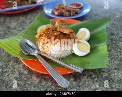 une assiette de riz salé sauce aux épices avec anchois frits sur feuille de banane Banque D'Images