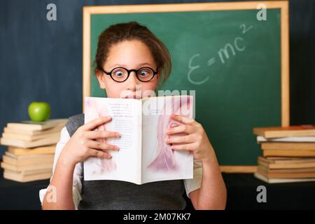 Captivé par le scénario. Une jolie fille brune qui regarde fascinée par le livre qu'elle est en train de lire. Banque D'Images