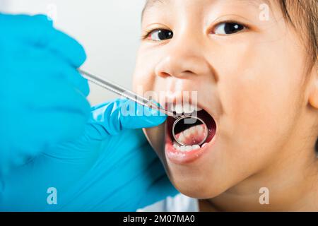 Le médecin examine la cavité buccale du petit enfant utilise le miroir de la bouche pour vérifier la cavité des dents Banque D'Images