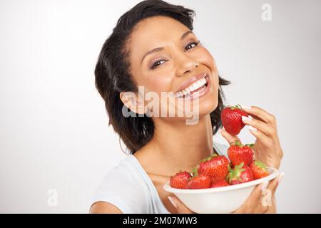 Shes a choisi l'alternative saine. Portrait d'une jeune femme appréciant un bol de fraises. Banque D'Images