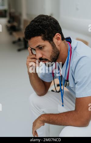 Vue en grand angle du médecin fatigué, assis dans le couloir de l'hôpital. Banque D'Images