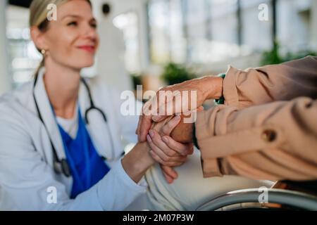 Gros plan de la jeune femme médecin tenant les mains de la patiente, la consolant. Banque D'Images