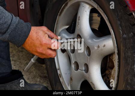 Auto mécanicien homme avec un tournevis électrique changer le pneu à l'extérieur. Service de voiture. Remplacer les pneus des roues à la main. Concept d'installation des pneus Banque D'Images