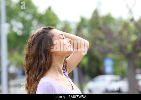 Profil d'une femme qui respire en touchant les cheveux dans la rue Banque D'Images