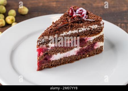 Gâteau à la cerise sur une assiette en porcelaine blanche sur une table en bois Banque D'Images