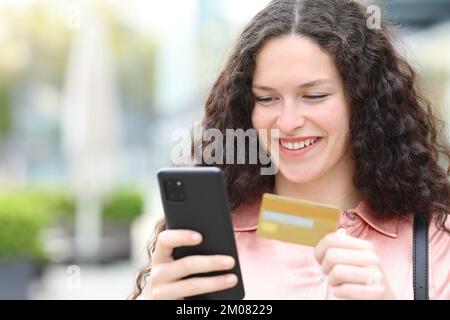 Femme payant avec une carte de crédit et téléphone smert marchant dans la rue Banque D'Images