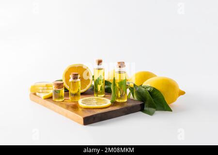 plusieurs bouteilles avec un couvercle avec un remède naturel de citron se tiennent sur un panneau de bois parmi les tranches et les fruits de citron. autosoins organiques. aromathérapie Banque D'Images