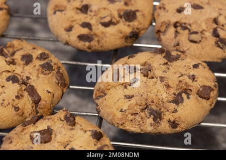 Biscuits aux pépites de chocolat faits maison sur une grille de refroidissement. Sur fond de pierre sombre Banque D'Images
