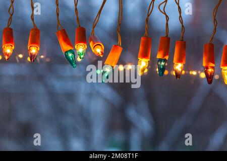 Illuminations de Noël - des ampoules vintage brillantes de différentes couleurs dans la fenêtre au crépuscule Banque D'Images