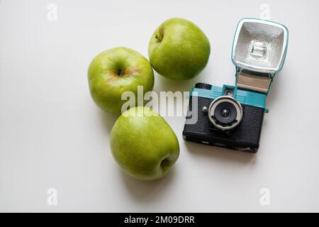 Trois pommes vertes et un appareil photo-film isolés sur fond blanc Banque D'Images