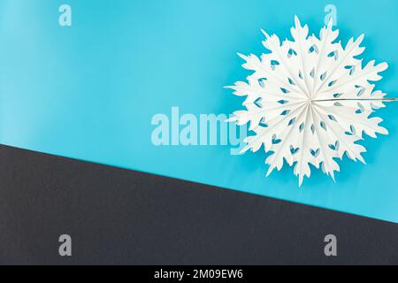 Flocon de neige en papier volumétrique sur fond coloré, plat. Banque D'Images