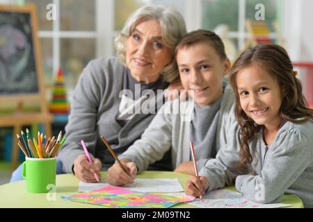 Portrait de la grand-mère avec les enfants dessinant à la maison Banque D'Images