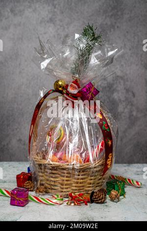 Cadeau du nouvel an. Cadeau de Noël avec panier sur fond gris. Paquet préparé avec du chocolat, des noix, des en-cas Banque D'Images