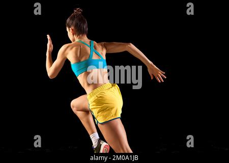 Vue arrière de la femme sportive, de la coureuse et du jogging en mouvement, isolée sur fond noir. Sport, fitness, énergie, mouvements concept Banque D'Images