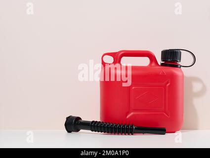Bidon en plastique rouge pour carburants liquides et lubrifiants sur fond beige, espace de copie Banque D'Images