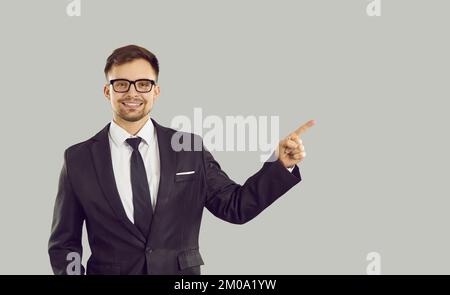 Jeune homme de race blanche positif pointant du doigt vers l'espace de copie habillé en costume d'affaires Banque D'Images