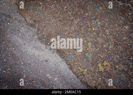 Fuite d'huile ou d'essence d'une voiture sur une route asphaltée mouillée et fissurée. Banque D'Images