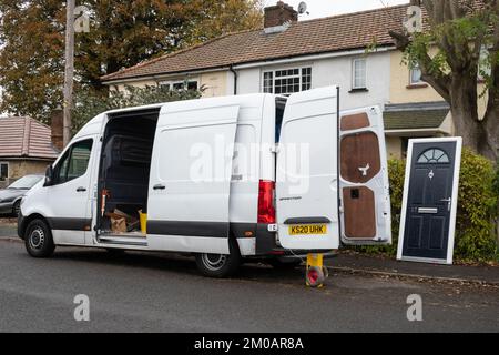 Fourgonnette blanche garée à l'extérieur des maisons avec une nouvelle porte de remplacement prête à être mise en place, Royaume-Uni Banque D'Images