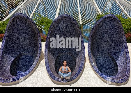 Femme méditant à la Cité des Arts et des Sciences, Valence, Espagne. Assis à pieds croisés au soleil Banque D'Images