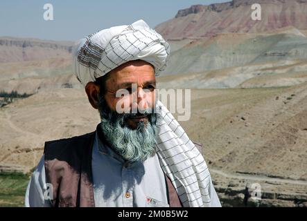 Village entre Herat et Qala-e-Naw, province d'Herat / Afghanistan : un afghan local portant un turban avec une toile de fond de paysage de montagne. Banque D'Images