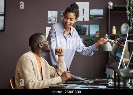 Équipe créative Posive discutant des photos de paysage qu'ils se sont préparés à télécharger sur le Web Banque D'Images